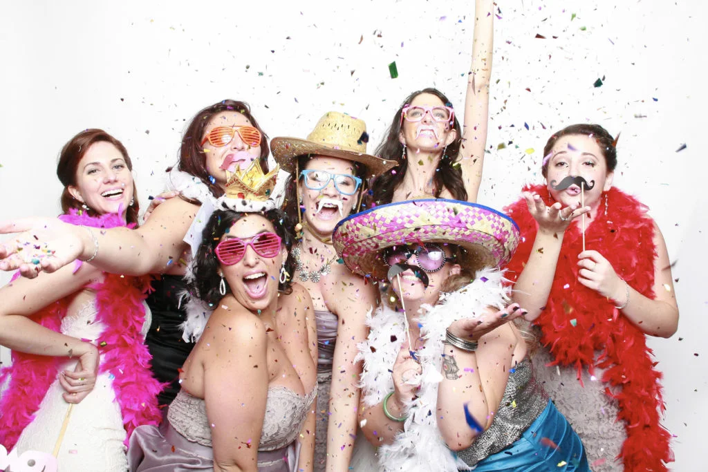 Photobooth A group of women posing in a photo booth at an Atlanta wedding, surrounded by confetti.