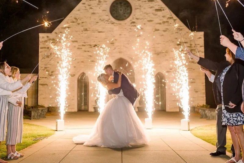 exquisite-sounds-special-Effects A bride and groom kissing in front of a church with sparklers.